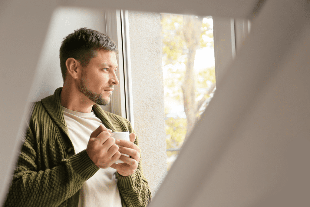 Men looking out of window with cup of tea - Men's Mental Health